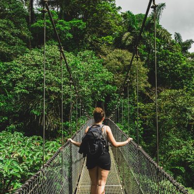 woman in black jacket and black pants standing on hanging bridge